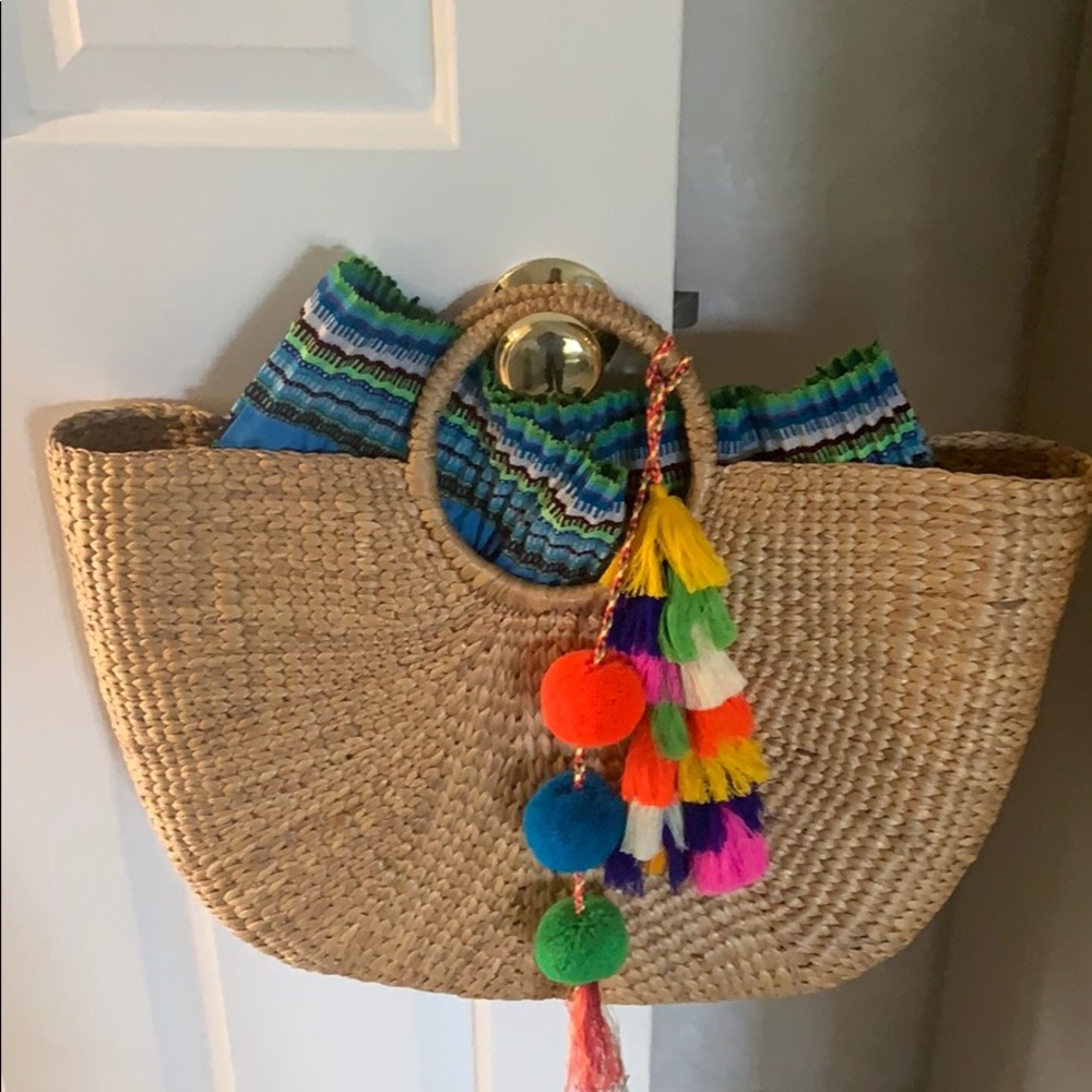 Hand held Jadetribe  straw bag with tassel.